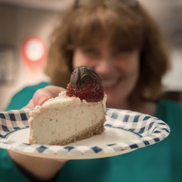 Une employée fière de présenter une part de son gâteau au fromage