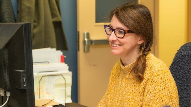 Une employée sourit devant son écran de travail.